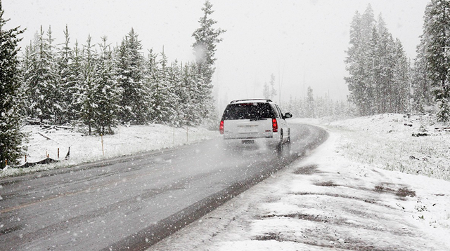 The back of a car driving through a wintry, snowy road